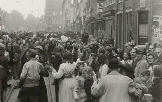 Feestvierende mensen in de Grote Houtstraat tijdens de Bevrijding. Foto uit het Noord-Hollands Archief